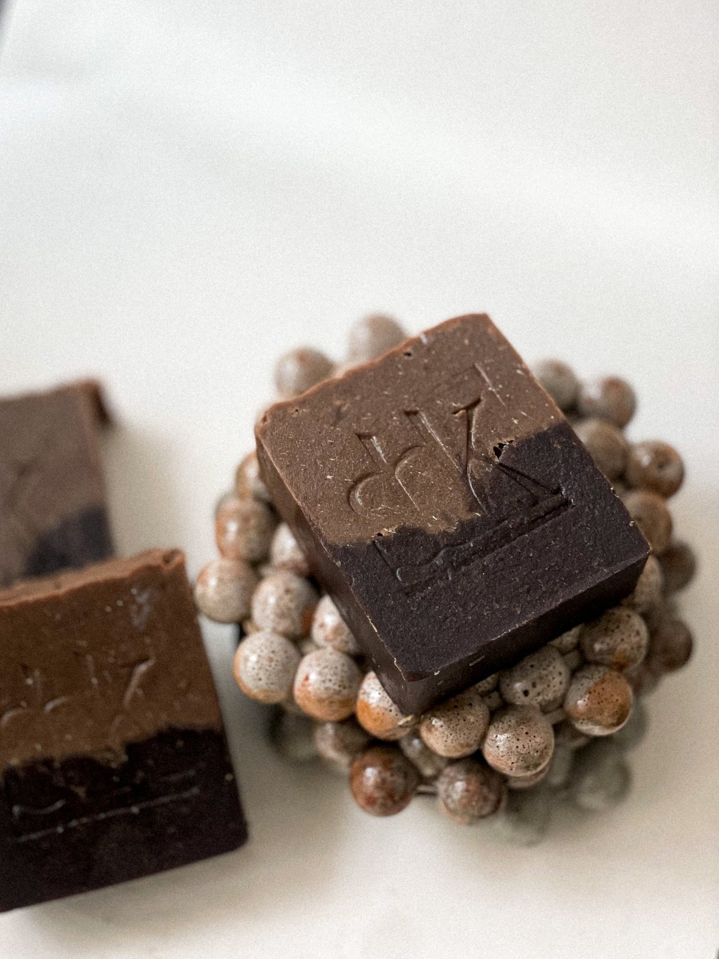 Cocoa and goat milk soap with SBK logo on a concrete soap dish