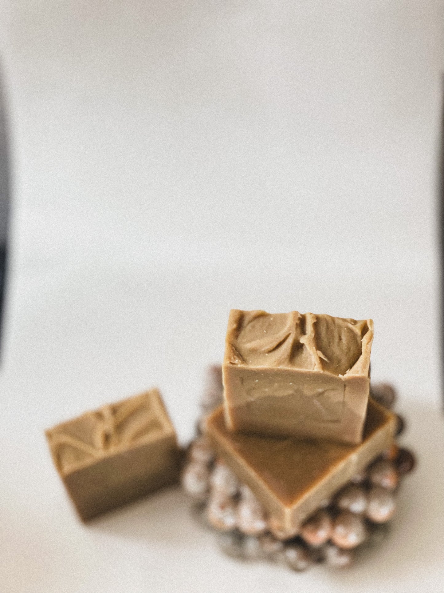 Three bars of brown soap on a white surface with a blurred background