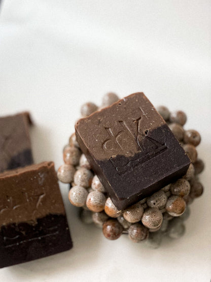 Cocoa and goat milk soap with SBK logo on a concrete soap dish