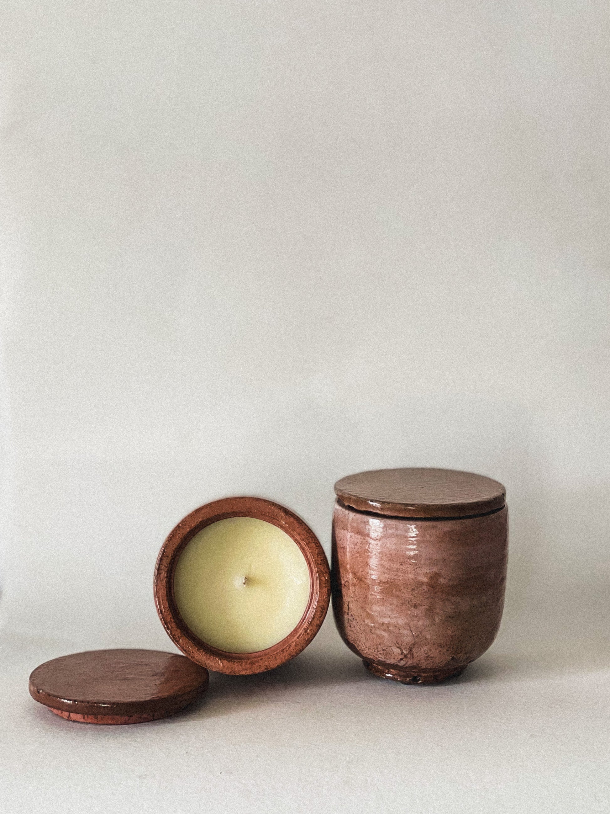 Concrete jar with a candle inside on a plain background.