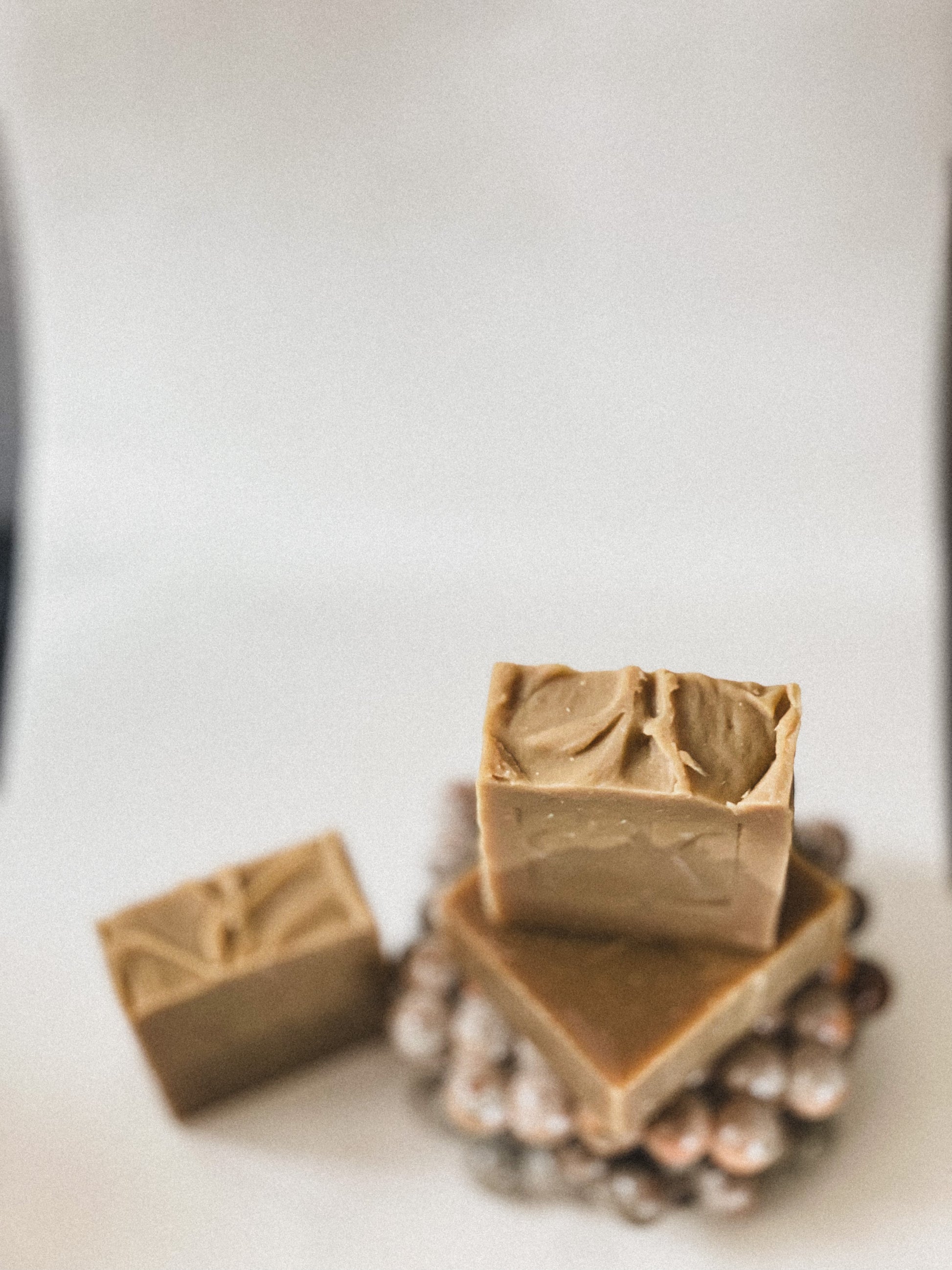 Three bars of brown soap on a white surface with a blurred background